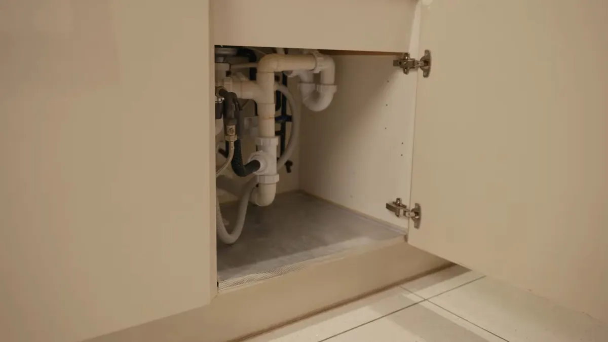 Open under-sink cabinet with exposed drain and supply connections during kitchen plumbing & remodel in surprise, az