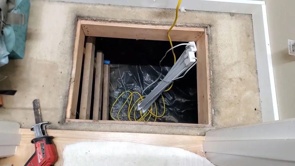 Open crawlspace access with inspection cables and plumbing equipment below the floor during sewer camera inspection in surprise, az