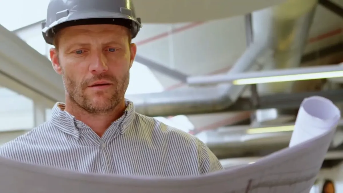 Contractor in a hard hat reviewing plumbing plans illustrating spring training rental plumbing prep in surprise, az