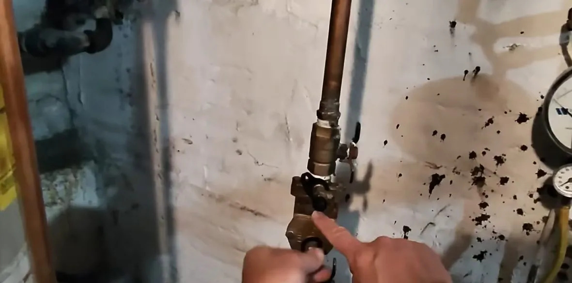 Technician tightening an indoor gas-line valve and pipe connection during plumbing service in Waddell