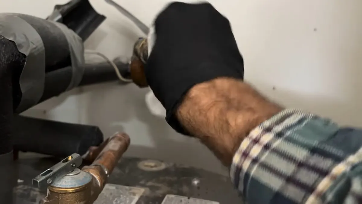 Technician tightening a leaking copper valve and pipe connection illustrating surprise az water bill mystery: leak or normal use?